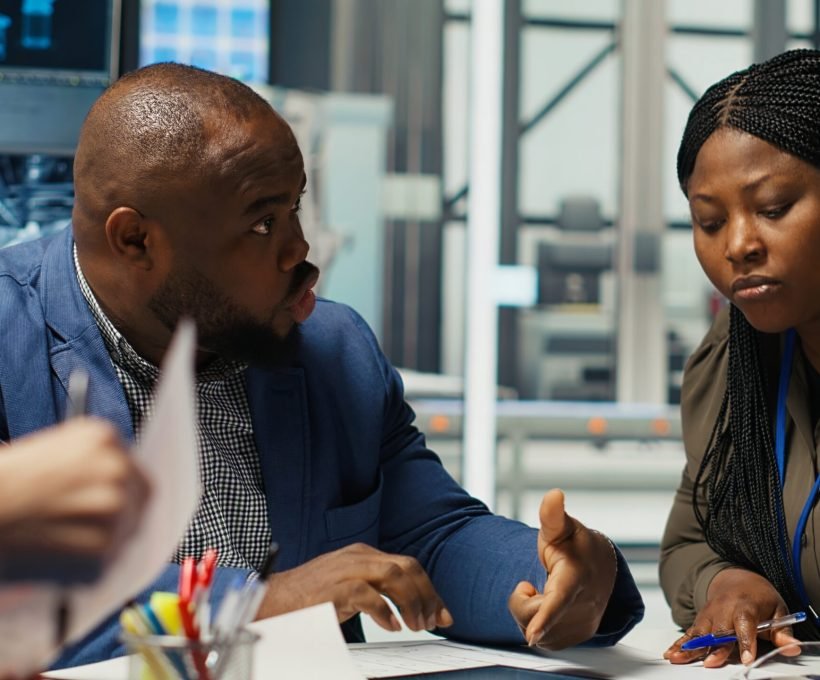 Factory engineering team look at assembly lines designs, working to increase energy output. Photovoltaics plant experts brainstorm innovative solar cell prototypes, looking over schematics, camera B